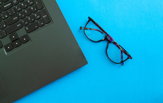 Desktop. Laptop and glasses on a blue background.