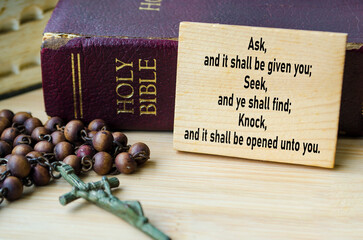 Ask, Seek and Know prayer text on wooden block with Holy Bible and Holy Rosary background....