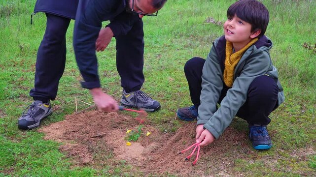Father working on the garden toghether with his son on an autumnal day