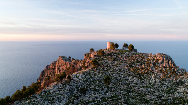 Aerial view of Torre del Verger standing proud atop rugged cliffs overlooking the vast, tranquil sea, kissed by the soft hues of dawn., Palma de Mallorca, Balearic Islands, Spain.