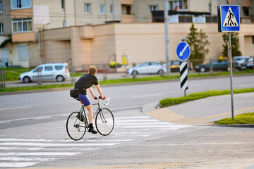 City crosswalk with cyclist moving across white zebra lines during daytime commute highlighting...