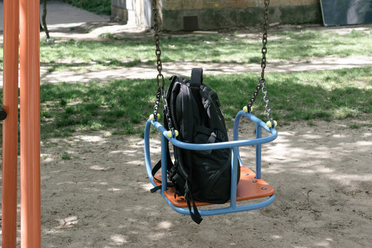 Black backpack on a swing at a playground