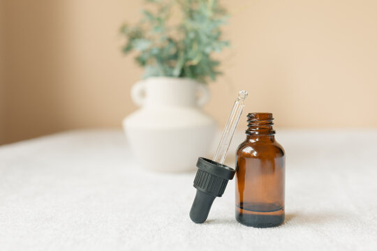 Simple amber essential oil dropper bottle with fresh wattle leaves