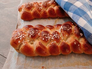 Side view of two just baked, fresh sweet plait with some pearl sugar. 