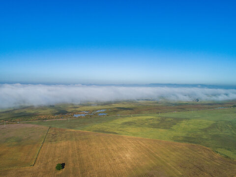Low cloud obscuring horizon lifting off rural farmland paddocks