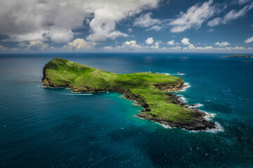 Aerial view of Coin de mire island, a jewel amidst the vast turquoise ocean, framed by a soft sky, Mauritius.