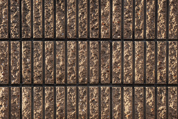 Close-up of a textured brown and black brick wall, showing vertical lines.