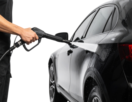 A person pressure washes a black SUV, cleaning its side and rear wheel against a dark background.
