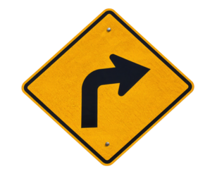 A yellow diamond-shaped traffic sign with a bold black right turn arrow indicating a sharp right curve ahead.