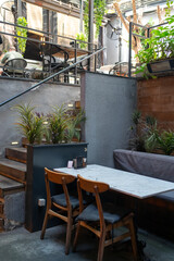 Stylish cafe corner with wooden chairs, a marble table, and potted plants creating a relaxed and modern atmosphere