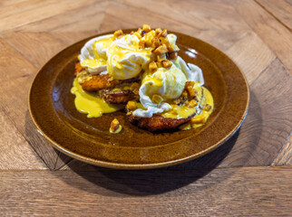 Gourmet breakfast presentation of crisp hash brown cakes layered under silky poached eggs drizzled with hollandaise