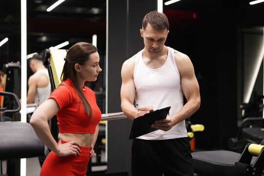 Young woman with professional personal trainer in gym