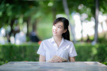 In a quiet corner of the university garden, a beautiful and cute female student from the...