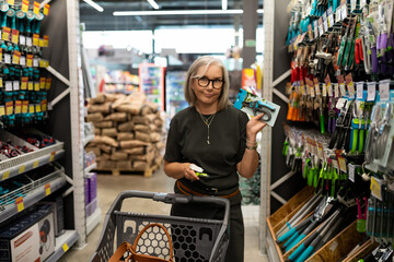 Middle-aged woman shopping in a large home improvement store with diverse products for her home and...