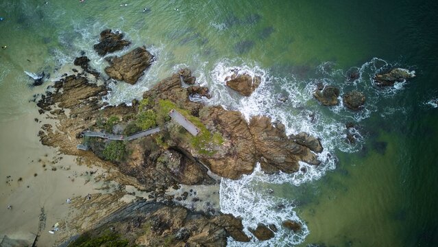 Aerial view of rocky coastline with vibrant ocean colors.