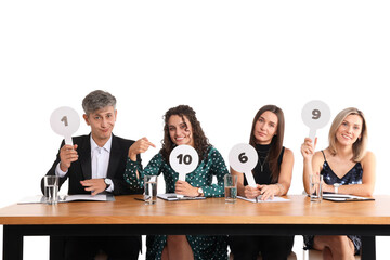 Panel of judges voting with score signs at table on white background