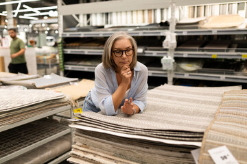 Woman thoughtfully selecting home decor items in a retail store while shopping in a hypermarket...