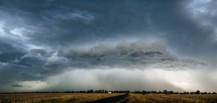 A large, ominous storm cloud formation over an expansive landscape.