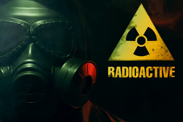 Man wearing gas mask in smoke against black background. Radioactive sign near him