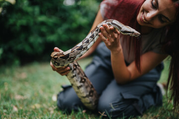 A cheerful girl interacts with a snake in a lush green outdoor environment, showcasing a bond with...