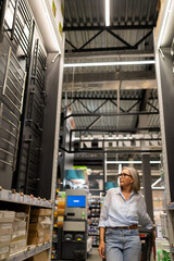 Middle-aged woman explores retail space in a home improvement store while shopping for household items and garden supplies