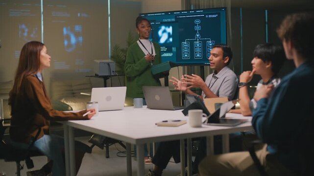 African American woman leader and programmer guides diverse team meeting in modern office. group collaborates on technology project with intense focus and determination