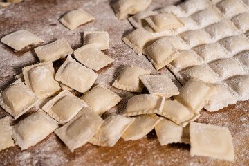 Fresh ravioli sprinkled with flour resting on wooden cutting board