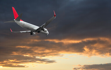 Airplane flying in beautiful sky with clouds at sunset
