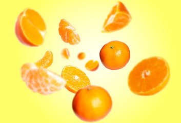 Juicy tangerines swirling in air against yellow background
