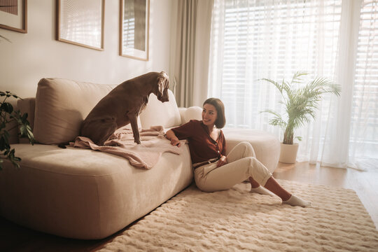 Cozy Indoor Moment A Woman Enjoys Quality Time with Her Dog While Sitting on a Sofa