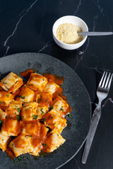 Ravioli pasta with tomato sauce and parsley on dark plate. Vertical Orientation