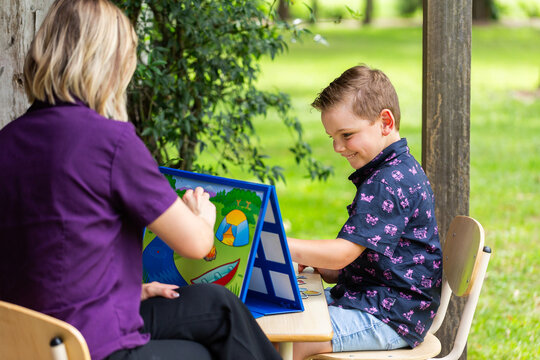allied health professional speech therapist working with boy in rural location on farm verandah