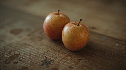 Closeup Photograph of Two Small Apples with Red Skin on Rustic Wooden Table Surface