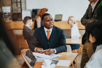 Colleagues collaborate around a table, reviewing documents and sharing ideas in a casual...