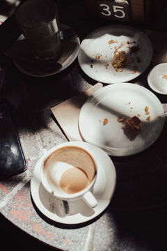 a moody scene in a cafe with a table cluttered with dirty dishes post-breakfast.
