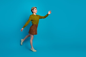 Stylish young woman in casual outfit posing confidently against a vibrant blue background capturing...