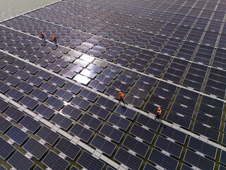 Professional workers clean and inspect solar panels on a floating buoy. Power plant with water	

