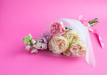 Beautiful small bouquet with pink and white roses on a pink background.Close-up.