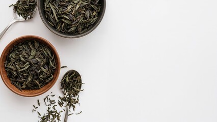 Fototapeta premium Dry tea leaves displayed in bowls and spoons for a ceremonial tea setup, captured from above on a white background with space for writing