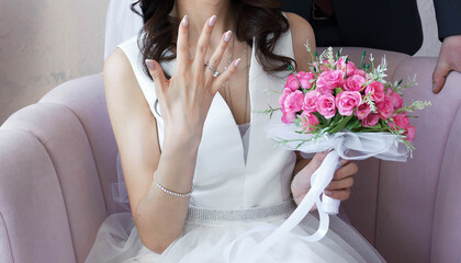 The bride shows the ring on his finger and smiles. a bouquet of flowers