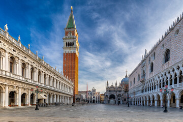 View of St. Mark's Square, where historic buildings frame the Campanile under a blue sky with light clouds, creating a captivating scene, Venice, Veneto, Italy.