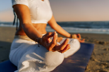 Hand in mudra during beach meditation at sunset