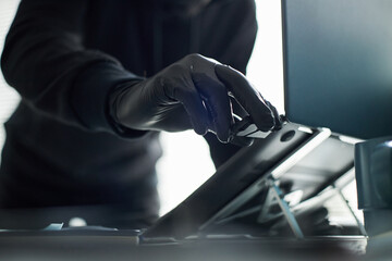 Unrecognizable man wearing black gloves breaking in and accessing laptop in office, inserting flash...