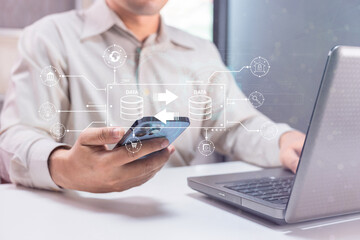 A person using a smartphone and laptop with digital data transfer and cloud computing icons overlayed, symbolizing technology and data management.