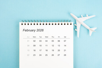 February 2026 calendar and airplane toy on blue color background, Travel plan concepts.