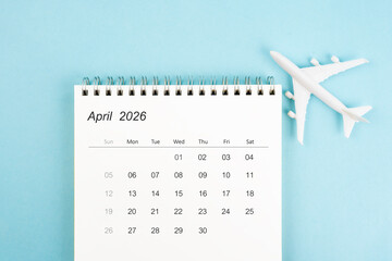 April 2026 calendar and airplane toy on blue color background, Travel plan concepts.