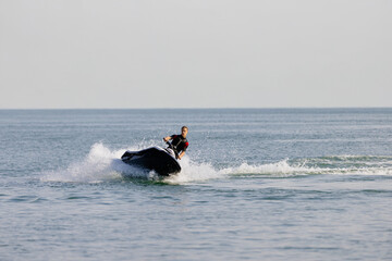 A young guy enjoying a fast ride on a jet ski under the summer sun. Concept thrill, freedom, and...