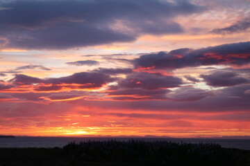 sunset with vibrant colors of orange, red and purple reflected in the clouds after a storm