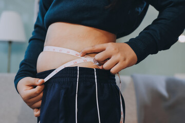 woman's hand holding excessive belly fat, overweight concept