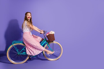 Young woman riding a retro-style blue bicycle on a playful violet background showcasing a cheerful summer lifestyle